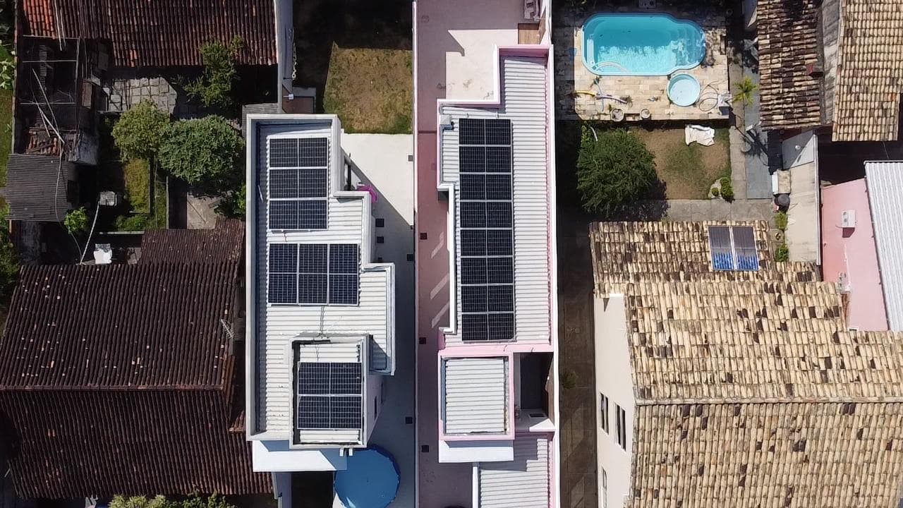 Vista aérea de imóvel com painéis solares no telhado e piscina ao lado